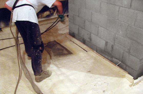 The foam can be walked on only minutes after spraying, permitting multiple layers without significant delay. The 2x4 at this chimney base will be removed after spraying to provide the code-required gap between the flue and the foam.