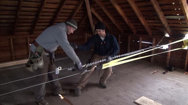 After reinforcing the rafter system and installing structural trusses and collar ties, carpenter Shane Fenton and project manager Mark Pollard ease off on the comealongs they had used to pull the outside kneewalls into alignment.