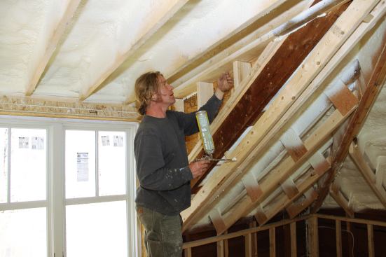 Armed with a can of foam sealant, carpenter Dale Cunningham feels for air intrusion with the back of his hand.