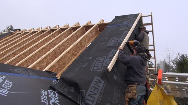 Installing a nailer on the opposite side of the roof. The first outrigger has already been nailed on.