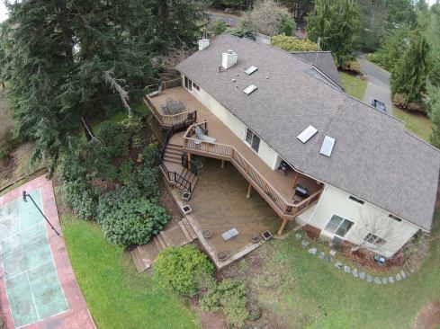 Designed for entertaining, the deck on this Woodinville, Washington home has angled steps that lead down to a stone paver patio and nearby sport court. The TimberTech Evolutions capped composite decking was also used to cap parts of the combo metal/wood railing and provide a flat surface for drinks.