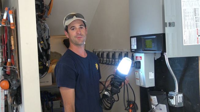 Bernard demonstrates the emergency-power capability of the Sunny Boy inverter by throwing the breaker serving the inverter at the house electrical panel, simulating a power outage. After switching on the emergency backup outlet, he plugs in a fluorescent job light—which works. With the panel putting out 3,000 watts on this sunny day, the emergency outlet could likely supply its maximum output of 1,500 watts as long as there continued to be sunshine.