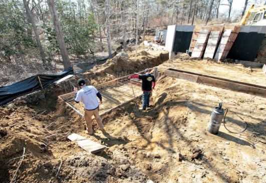 One crew began installing the septic system while another formed the attached garage foundation. The heavily reinforced spread footing will anchor a retaining wall that extends from the back wall of the garage.