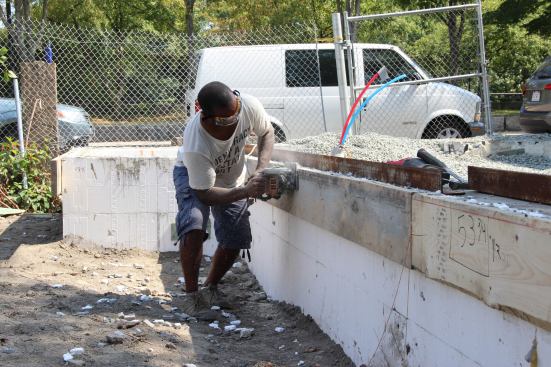 Scotland Willis installs guide boards for a concrete screed. The 2x10 boards are screwed to the plastic ribs in the ICF forms, then a level line is snapped on the boards and the boards are trimmed to create a level guide surface.