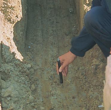 The author checks soil density in a footing trench using a penetrometer. Soil strength directly under the footing, where loads are concentrated, is crucial to foundation performance.