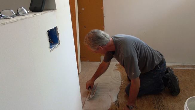 Boucher applies mortar to the subfloor in preparation for installing the Kerdi-Board curb.
