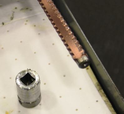 The file-like rod on the right is a broaching tool. It fits inside of a machine that pushes it through the center of the socket to size and finish (smooth) the square hole for the ratchet drive.