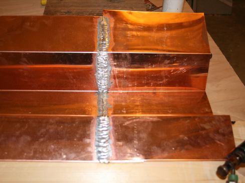 After soldering the vertical seam, I finish the sloped seam on leg running up the roof, starting from the bottom, working my way up. I turned the torch’s temperature up a little on this shallower slope. I then soldered crown-side vertical seam; and lastly, the horizontal leg covering the crown cap. On site, weather conditions impact soldering quite a bit and I tend solder by “feel”. When it’s cold or windy, you need more heat. Though not a hard-and-fast rule, I install only as much copper as I can solder in a day.