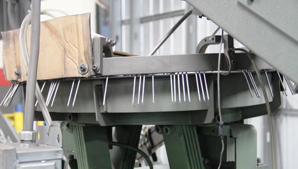 The nails come out of the rotary orienting feeder edge-to-edge—as they would be when collated—and are fed into device that forms rings on the shaft. 
Click here for video. The rings are made by the spinning gizmo at the end of the clip.