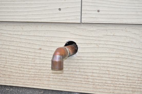 Plumber drilled a copper water heater drain pipe hole through the finished siding. Major Rookie Builder Mistake!