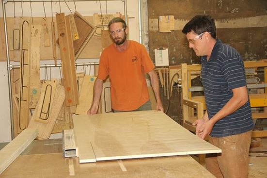 Jeff Cleveland and Joe Peters rip plywood into five-inch strips for use in building toe-kick bases for a set of custom cabinets.
