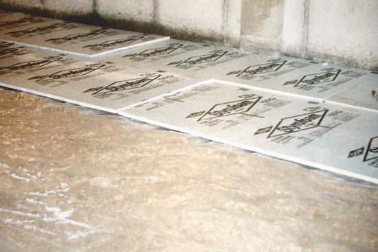 In preparation for pouring the basement slab, a layer of 1-inch-thick polystyrene insulation is installed over 6-mil polyethylene and 8 inches of crushed stone.