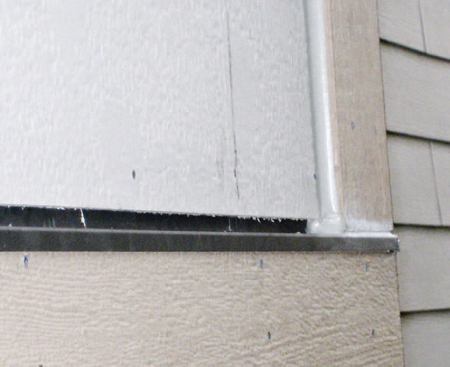 The block is sealed to the panel with sealant, but we left the joint between the bottom of the panels and the Z-flashing capping the trim at the chase base uncaulked, to allow any moisture that gets between the siding and the drainage plane to escape.