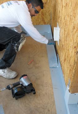 L-shaped flashings are installed at the transition between deck and wall. A slit in the bottom leg of this piece allows it to be folded into the corner.
