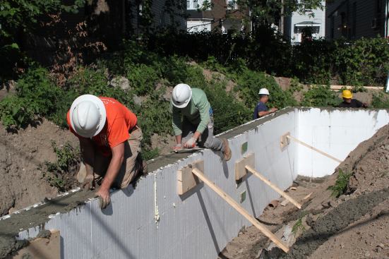 Workers strike the concrete level and trowel it flat on the day of the wall pour.