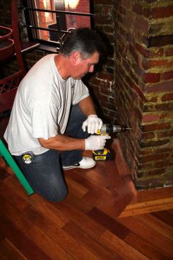 On site at La Famiglia Giorgio restaurant in Boston’s historic North End, a crew member drills into the mortar of the restaurant’s brick wall in preparation for hanging a “REVRB” sound-absorbing panel in place.