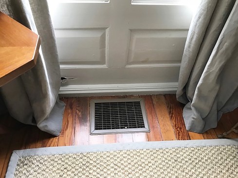 Cold air from a floor register is causing moisture to condense on a wood door, causing it to deteriorate. The moisture is likely coming from air leaks around the door. This moisture might not have been a problem if the surface of the door wasn’t frequently so cold.