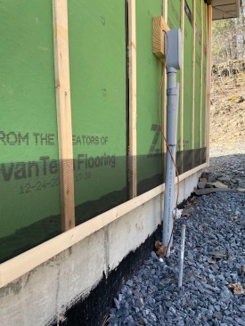 The bases of the furring strips are wrapped with insect screen, and a starter strip is installed at the base of the walls.