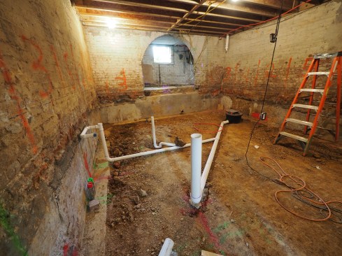 With the basement dug out, drainage lines and an ejector pump for a new bathroom are installed.