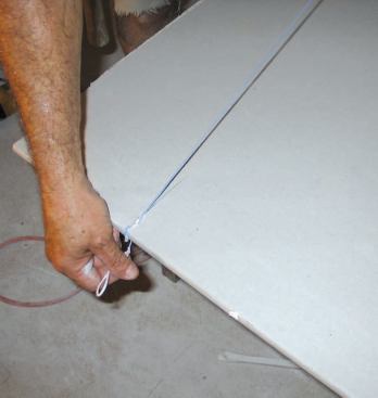 To lay out irregular cuts, he either fastens a straightedge to the panel with spring clamps or snaps a chalk line, making a short kerf in the panel to hold one end of the line.