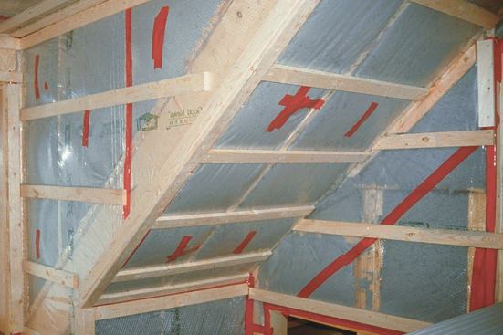 When the budget allows, 2x6 studs are spaced 24 inches on-center, and 1x3 strapping is installed horizontally at 16 inches on-center. The air space provides a thermal break between the studs and the drywall. Red 3M tape is used to seal seams and tears in the poly air barrier.
