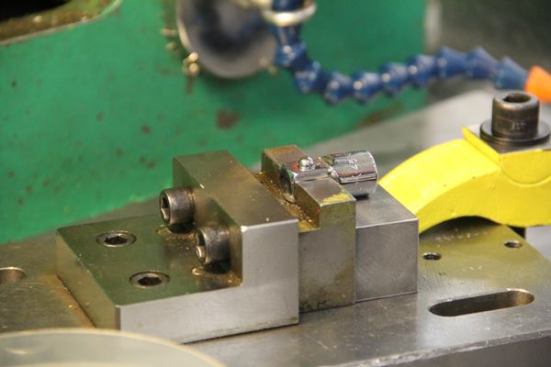 The retention bearing on the stem of this drive adapter has been placed over a spring in a hole. A press fitting tool will be used to push the bearing into the piece and deform the edges of the hole so it won’t fall out. The spring-loaded bearing will then be used to hold sockets in place on the adapter.