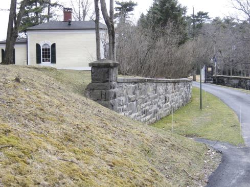The restored section of the wall stands perfectly straight. To save the mature plantings visible at rear, repairs were limited to the most severely affected section; parts of the original wall remain several inches out of plumb.