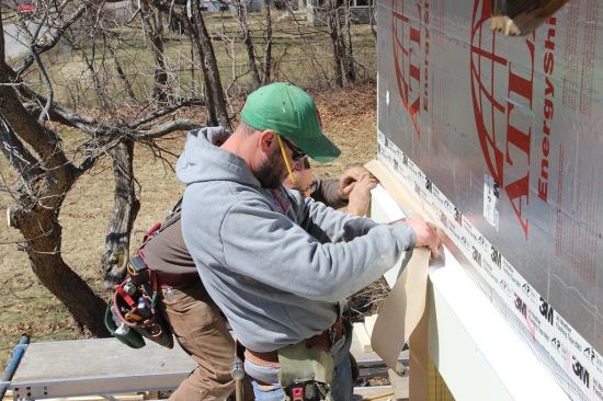 Nailing the cap flashing to the wall sheathing through the 3" of continuous rigid foam is impractical; instead, Pollard and carpenter Shane Fenton seal the flashing to the face of the rigid insulation using 3M 8067 flashing tape.