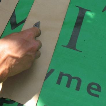 To further protect against water incursion with continuous flashing, Mike back-flashes with two strips of 4-inch flashing tape. First he scores the middle of the first strip.