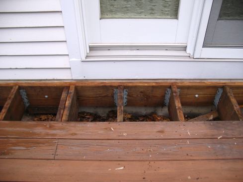 The ledger was connected to the house through the skirt board with a few lag screws and some nails. Note the absence of any ledger flashing.