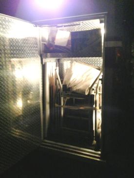 This photo is dark because it was taken at night. It's of the front left exterior compartment. Note the lights inside the compartment. The light coming down from above is from one of two scene lights on that side of the module.