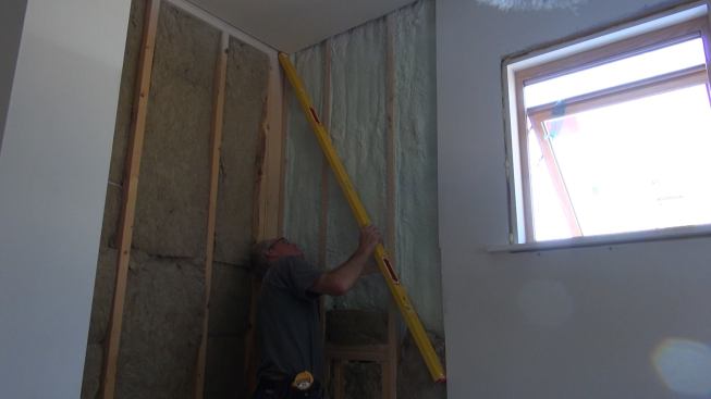 Tom Boucher checks the shower wall framing for flatness with a six-foot level. Framing tolerances are important in a tiled bathroom, because tile joints will reveal any irregularities in the substrate.
