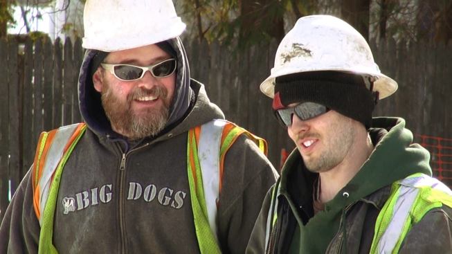 Ground crew members for the crane operator congratulate each other on the successful outcome of a tense and tricky operation.