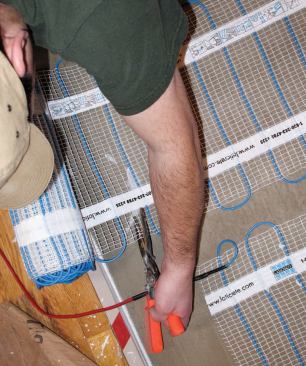 Laticrete's electric heat mats are designed to be cut to fit in the field and have a self-adhesive backing that holds them in place; tape and thinset are also useful to hold down edges and wiring connections.