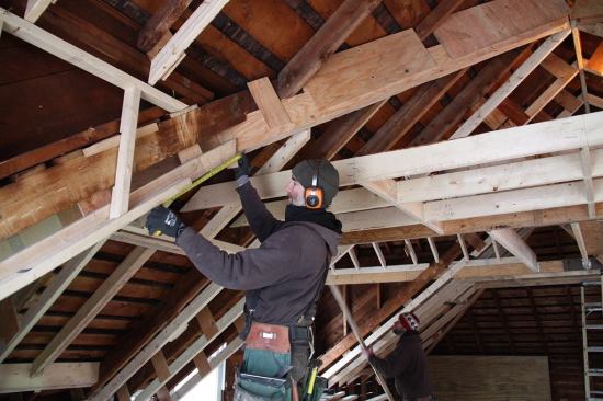 With the structural reframing and reinforcing of the roof completed, carpenter Ed Muennich works on the task of framing down the roof system to create space for insulation.