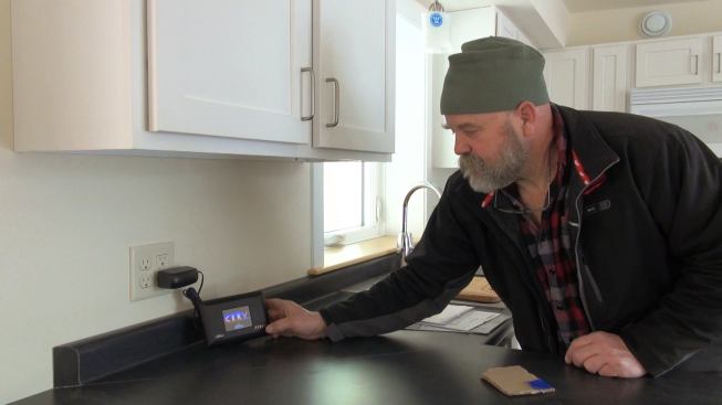 Steve Davis demonstrates the function of the remote control unit for the building's Conditioning Energy Recovery Ventilator. Once charged at the wall, the control can be unplugged and used anywhere in the building.