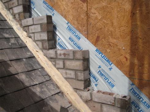 Executing a true through-wall counterflashing along the rake of a sloped roof requires installing a series of stepped pans. In this photo, the masons began by building up the brick in stair-step fashion. The rise and run of these stair steps will vary with the pitch of the roof, but each step will be the same rise and run because the slope stays the same and the brick coursing is the same.