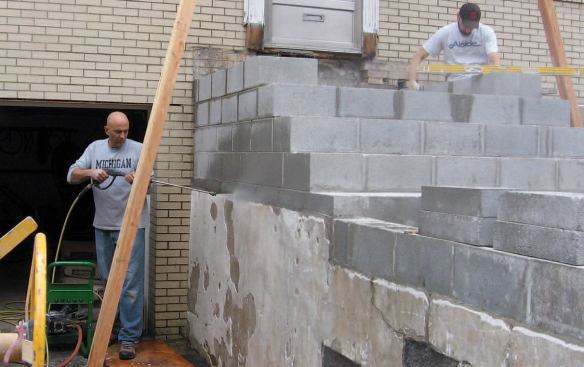 Once the blockwork was completed, we scraped, powerwashed, and patched the existing retaining walls and began parging everything before setting the limestone treads.