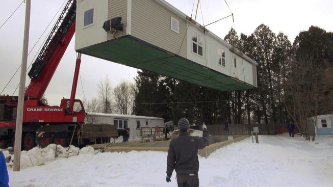 Peter Schneider of Efficiency Vermont passes signals to the crane operator as the team carefully eases the 70-foot house onto its stemwall foundation.