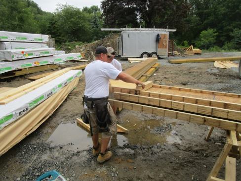 Framers test-fit blocking for nailing in a wood I-joist rafter.