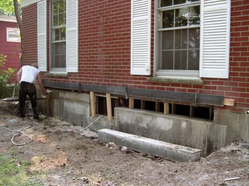 After sawing part of the way through a mortar joint, the author slid in this 18-foot-long 4x6 steel lintel to support the veneer. He clamped it to the band joist using threaded rod and lengths of angle iron so that it wouldn't slip out of place.