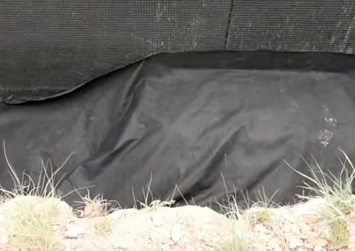 The fabric is pulled over the rock, adhering the edge to the fabric draped up the wall.
