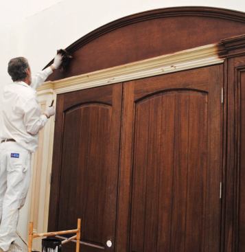 The stain is wiped off with a rag to remove the excess and even out the finish. After the stain has dried overnight, the trim will receive two coats of fast-drying vinyl sanding sealer.