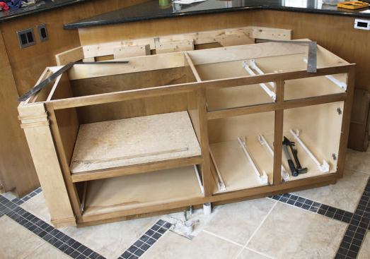 Evidently, the previous island had contained a sink. Unfortunately, this area of the floor would be in plain view after we reconfigured the cabinets, so we were going to have to remove the pipes and replace a couple of tiles.