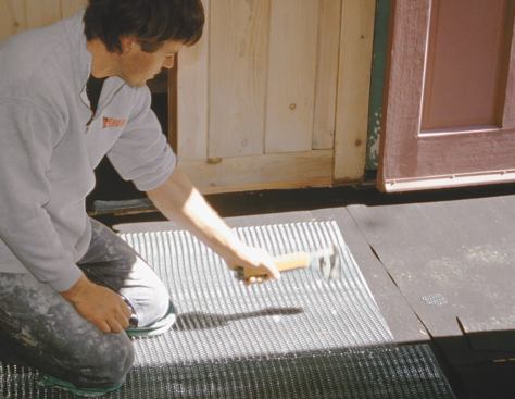 After covering the floor with 15-pound asphalt felt to retain curing moisture in the mud bed, the author staples reinforcing galvanized wire mesh over the entire surface.