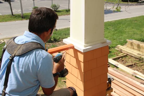 Attaching the railing to the porch column using #8 3-inch stainless steel screws.