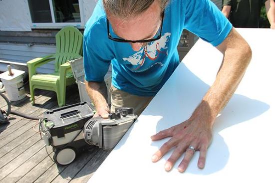 … and fine-tunes the joint using a belt sander.
