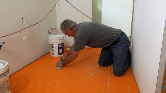 To ensure a good bond, Boucher presses the Ditra membrane onto the mortar bed using an 18-inch float.