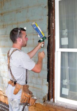 After removing trim from the old windows (this frame was fitted with new jamb liners and replacement sash), crew members filled voids and gaps around the frames with spray foam.