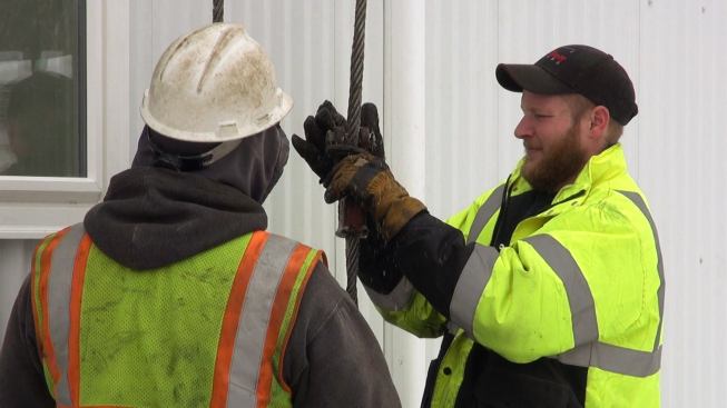 Crane crew members work on hooking up the lift cables.